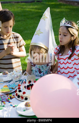 Girl blowing out candles on cake at Birthday party Banque D'Images