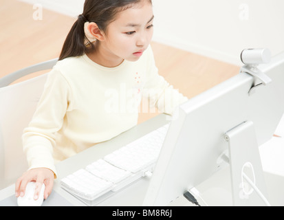 Une fille assise au bureau, ordinateur de bureau sur le bureau Banque D'Images