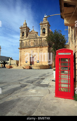 Une cabine téléphonique britannique rouge assise seule dans une case vide dans un cadre méditerranéen dans un village sur l'île de Gozo, Malte Banque D'Images