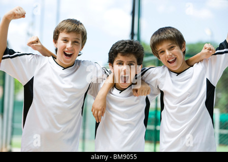 Les jeunes de l'équipe de soccer avec bras levés en signe de victoire, portrait Banque D'Images