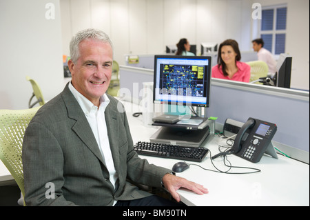 Smiling casual office worker dans un bureau d'étude de l'architecte avec le logiciel CAO affichée sur l'écran derrière Banque D'Images