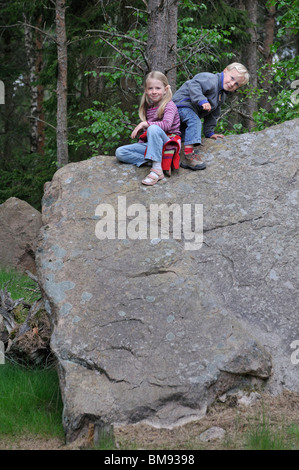 Jeune fille et un garçon assis sur un rocher dans Groenaasen forêt près de Kosta, Jonkopings Lan, Suède Banque D'Images