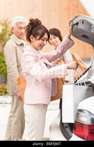 Jeune femme avec les parents choisir panier de boot Banque D'Images