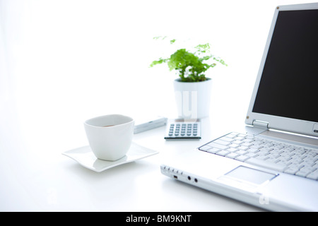 Ordinateur portable et tasse de café sur le bureau en exercice, fond blanc Banque D'Images