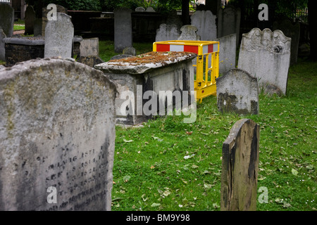 L'escrime de la construction parmi les pierres tombales de l'époque victorienne historique de Bunhill Fields cimetière dans la ville de Londres. Banque D'Images