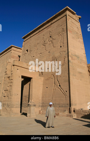 L'Homme égyptien en costumes traditionnels en dehors du Premier pylône du Temple d'Isis à Philae, bon maintenant sur l'Île Agilka en Egypte Banque D'Images