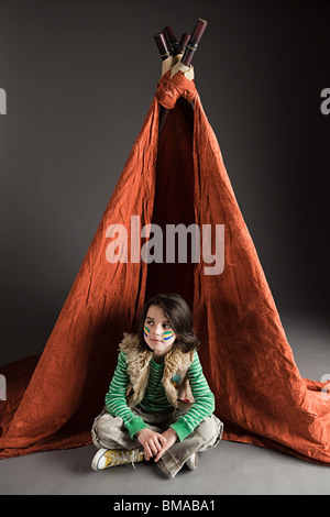 Jeune garçon habillé en costume Amérindien, avec tipi Banque D'Images