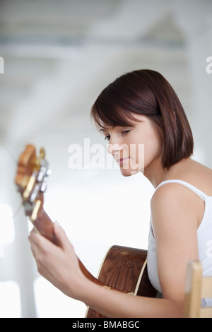 Femme assise avec guitare acoustique Banque D'Images