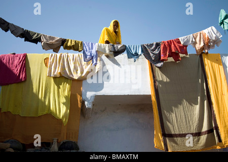 Le séchage des lingettes sur le toit et le fil jaune femme en sari à semi-urbaines ; village ; Dilwara Udaipur Rajasthan ; Inde ; Banque D'Images