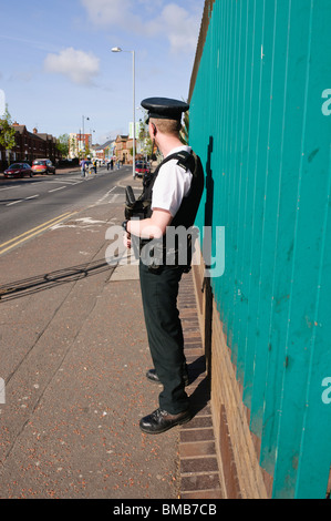 Agent de police armé avec un Heckler et Koch G36C fusil d'assaut, debout sur la Falls Road, une ligne de piquetage 'white' Banque D'Images