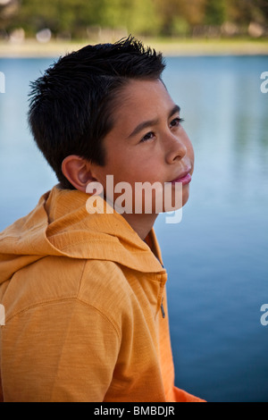 9-11 ans garçon américain Hispanique à l'extérieur en contemplant la vie. Une pensée rêve assis MR © Myrleen Pearson Banque D'Images