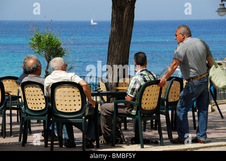 ST JULIAN'S, MALTE. Un groupe d'hommes assis et parler maltais par la baie de Balluta. Banque D'Images