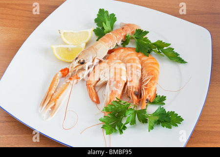 Crevettes et crevettes avec du citron et du persil sur une assiette blanche Banque D'Images