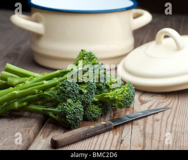 Le brocoli frais posé sur une table de cuisine en bois avec un couteau à légumes et une casserole avec couvercle à l'arrière-plan Banque D'Images