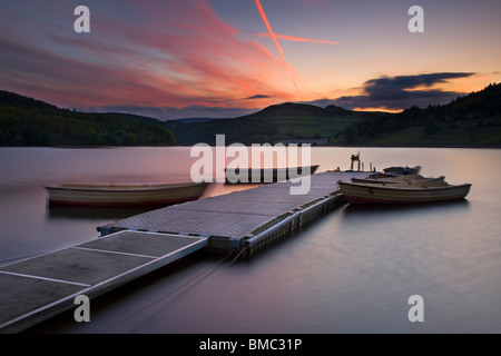 Coucher de soleil sur Ladybower Reservoir avec bateaux de pêche amarrés sur un ponton Pier, près de Bamford dans le Derbyshire Peak District, UK Banque D'Images