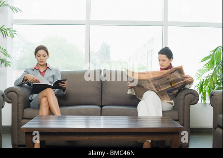 Businesswomen lisant le journal, magazine dans une salle d'attente Banque D'Images