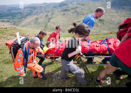 Un homme avec une blessure à la jambe est stretchered Langdale par des membres de l'équipe de sauvetage en montagne/Ambleside, au-dessus de Grasmere, Lake District, Banque D'Images