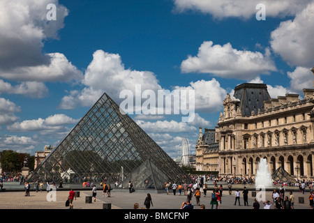 Vue panoramique de la pyramide de verre, des fontaines d'entrée de Louvre célèbre attraction français dramatique magnifique ciel bleu avec des nuages Paris France Banque D'Images