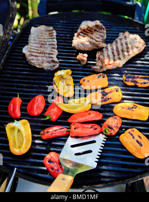 Les steaks et les poivrons sur la grille du barbecue Banque D'Images