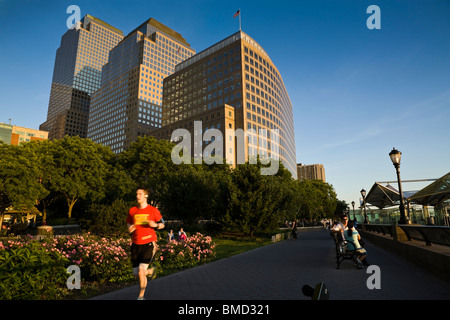 Un homme jouit d'une vue panoramique sur le fleuve Hudson, à New York tout en tournant le long d'un chemin dans Battery Park City. Banque D'Images