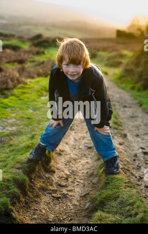 Jeune garçon rire et jouer en marchant au coucher du soleil dans la campagne. Banque D'Images