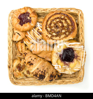 Vue de dessus de panier en osier avec sélection de pâtisseries danoises et françaises sur fond blanc. Banque D'Images