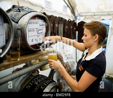 Un travailleur féminin bar versant une pinte de vraie bière à la fête de la bière du cerceau en stock dans l'Essex. Banque D'Images