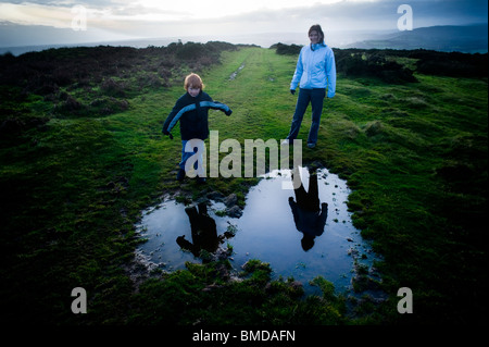 Mère et son leur reflet dans une flaque en forme de coeur en marchant dans la campagne galloise Banque D'Images