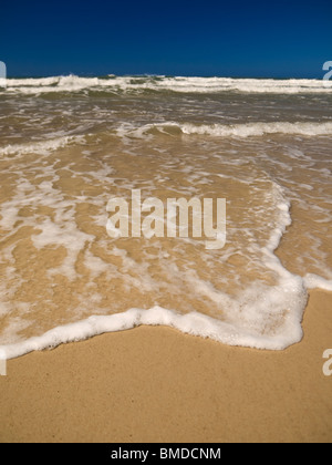 Une petite vague est venue à la plage de sable. Banque D'Images