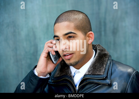 Les jeunes professionnels urbains dans son début des années 20 portant un costume sombre parlant sur un téléphone cellulaire. Banque D'Images