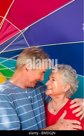 La retraite en bonne santé senior couple smiling ihappy sous parapluie coloré à l'extérieur Banque D'Images