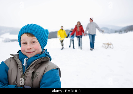 Garçon à l'extérieur en hiver avec la famille Banque D'Images
