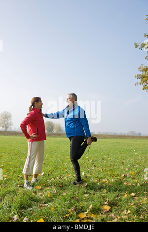 Couple Stretching in Field Banque D'Images