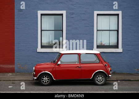 Classic mini rouge garée devant une maison bleue. Banque D'Images