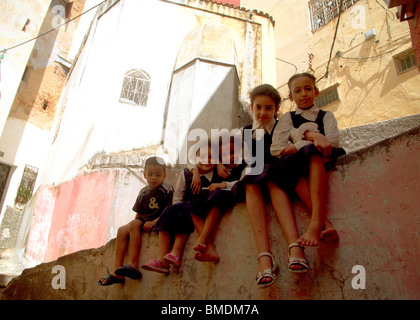 Des écoliers marocains assis sur un mur sous la tombe du voyageur du XIVe siècle Ibn Battuta, à Tanger Banque D'Images