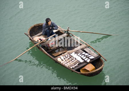 Jeune fille de coquilles vente bateau à Halong Bay, Vietnam Banque D'Images