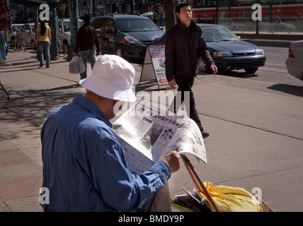 Un homme lisant un journal chinois est vu dans le quartier chinois de Toronto Banque D'Images