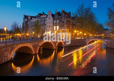 Traces légères à partir d'un bateau de croisière en passant sous les ponts illuminés de Keizersgracht et Leidsestraat Amsterdam Pays-Bas Banque D'Images