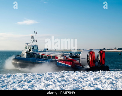 Aéroglisseur fonctionnant dans le Solent entre Portsmouth et l'île de Wight avec une plage couverte de neige en premier plan Banque D'Images