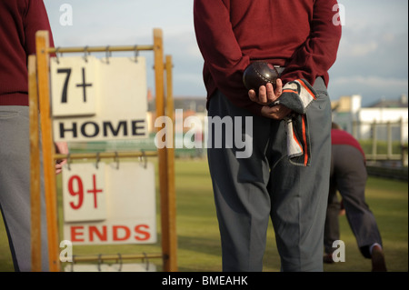 Vue arrière du les hommes âgés moyens de jouer à un jeu de boules vert pelouse un soir d'été, Aberystwyth Wales UK Banque D'Images