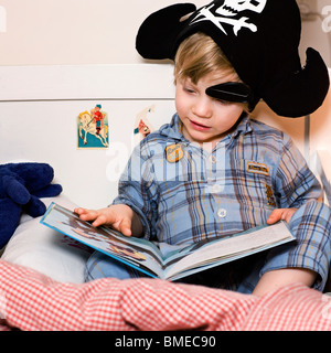 Boy reading book on bed Banque D'Images