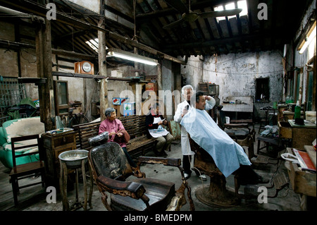 Personnes âgées coiffure donnant son client une coupe dans un salon de coiffure, Shanghai, Chine Banque D'Images