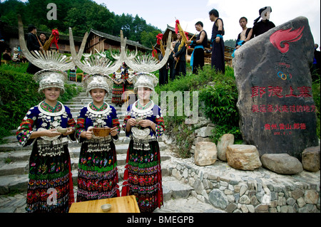 Les jeunes femmes Miao touristes accueil avec du vin dans la région de Langde, village du comté de Leishan, Kaili, province de Guizhou, Chine Banque D'Images