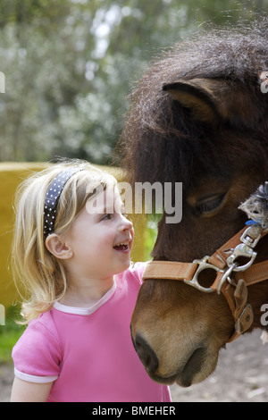 Petite fille blonde adore son pony funny portrait Banque D'Images