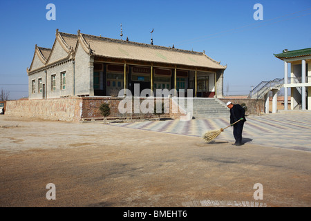 Homme Hui balayer la cour de la mosquée, Mageda Mageda Village, Tongxin, Wuzhong, province de Ningxia, Chine Banque D'Images