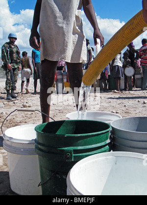 Une fille regarde les casques bleus des Nations Unies de remplir des seaux avec de l'eau potable dans les zones semi-désertiques à l'extérieur de Gonaïves, Haïti Banque D'Images