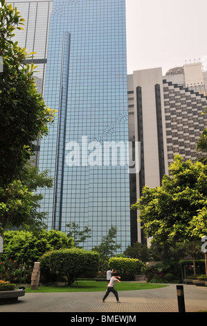 Deux personnes pratiquant des exercices de Tai Chi dans un petit parc avec un gratte-ciel en toile de fond, près du front de mer à Central, Hong Kong Banque D'Images