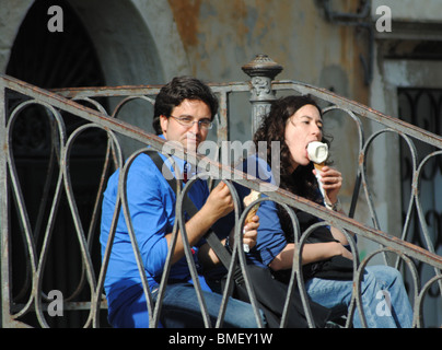 Les touristes de manger des glaces, assis sur un pont à Venise, Italie Banque D'Images