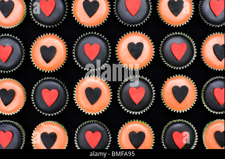 Mini cupcakes décorés de glaçage orange et noir et des formes du coeur Banque D'Images