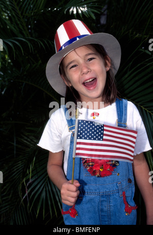 Une magnifique jeune fille dans un chapeau de l'Oncle Sam patriotique vagues le drapeau américain lors d'un 4 juillet holiday parade en Floride, USA. Banque D'Images